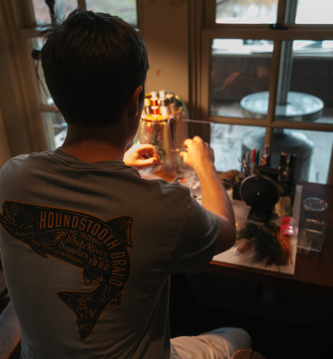A grey shirt with an orange trout on it, inside the trout it says Houndstooth Brand.