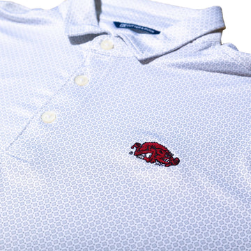 Close-up of a white patterned polo shirt with a red embroidered Arkansas Razorbacks Slobbering Hog logo on the chest 