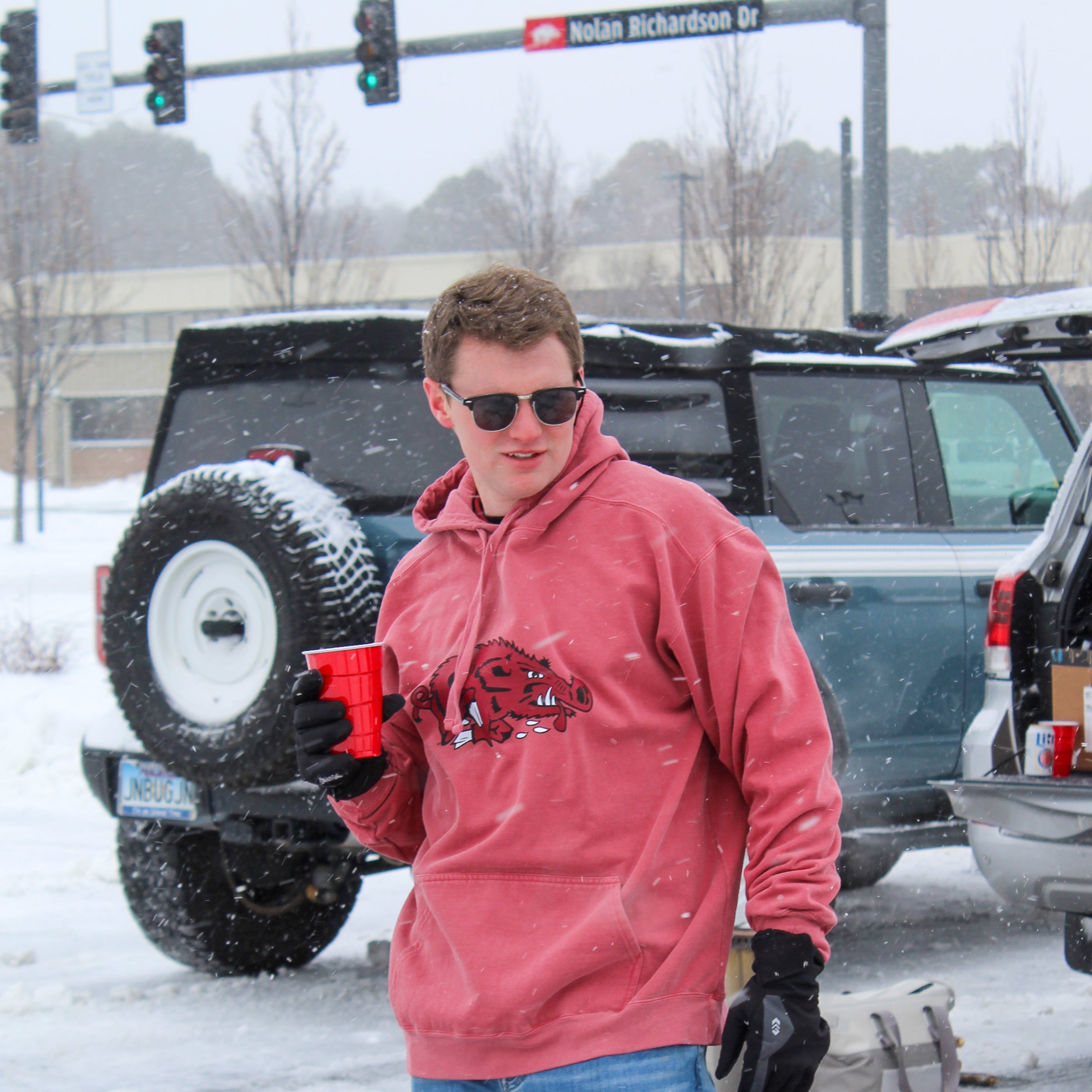 Person wearing a red Slobbering Hog Razorback basketball hoodie in the snow.