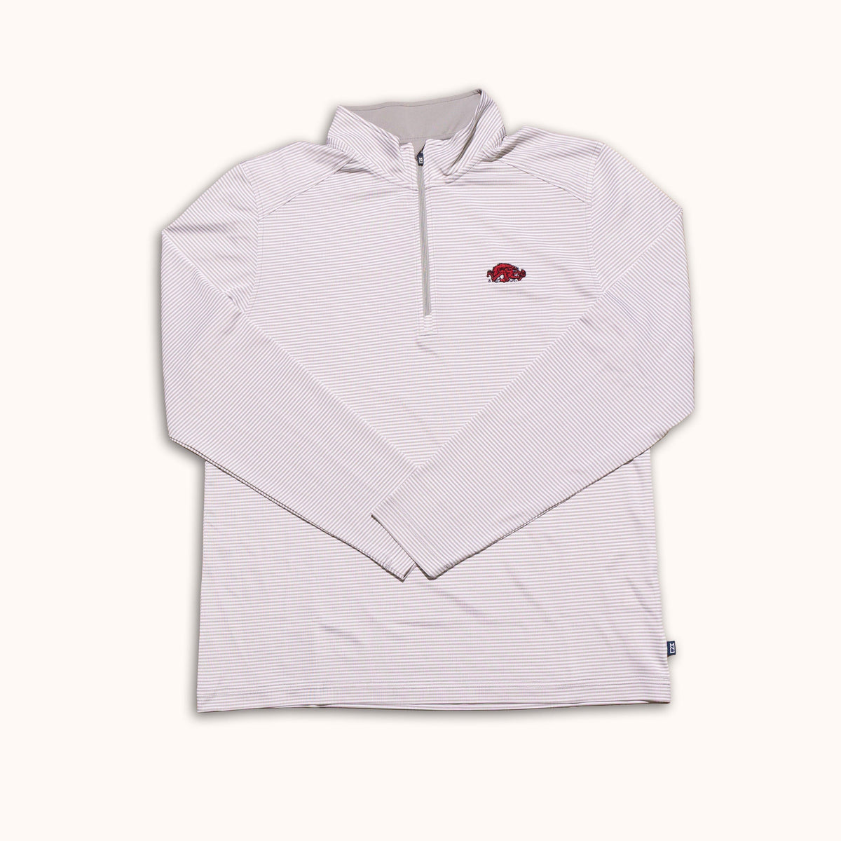 A light pink and white striped long-sleeve quarter-zip pullover with a small red Arkansas Razorbacks logo on the left chest, displayed flat against a cream background.