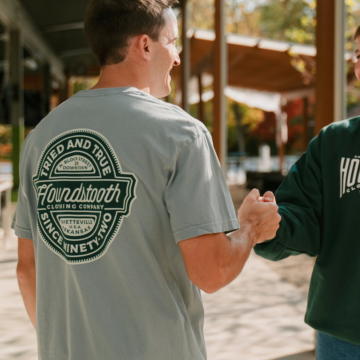 Two men wearing Houndstooth brand clothing outdoors.