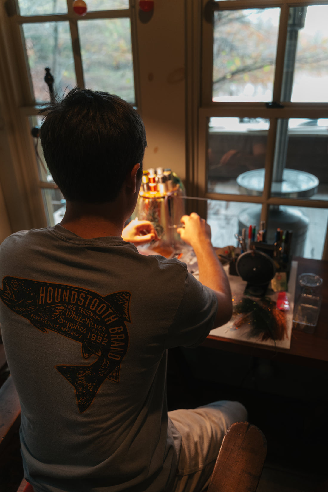 A grey shirt with an orange trout on it, inside the trout it says Houndstooth Brand.