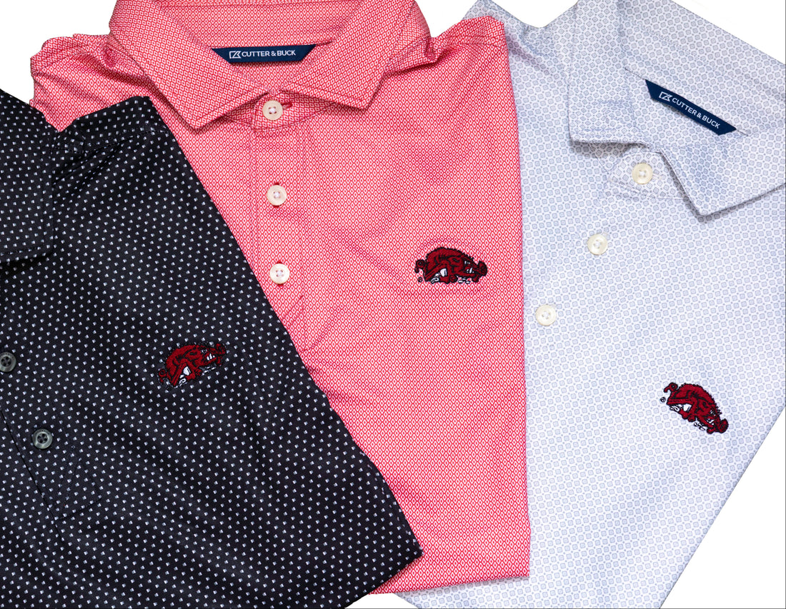 Close-up of a white patterned polo shirt with a red embroidered Arkansas Razorbacks Slobbering Hog logo on the chest 